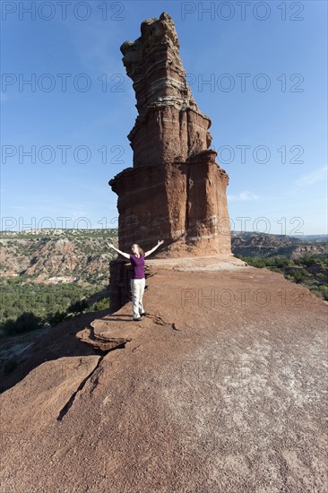 Woman with arms outstretched standing by rock formation