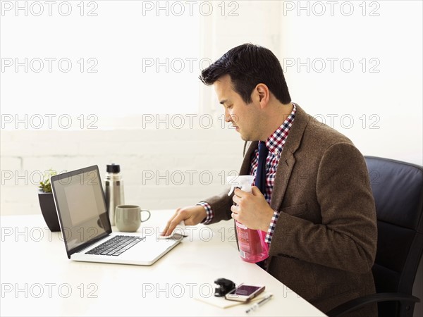 Businessman cleaning laptop in office