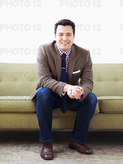 Man in suit sitting on sofa and posing to camera