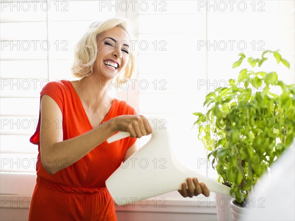 Woman in red dress watering potted plant