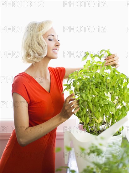 Woman in red dress touching potted plant