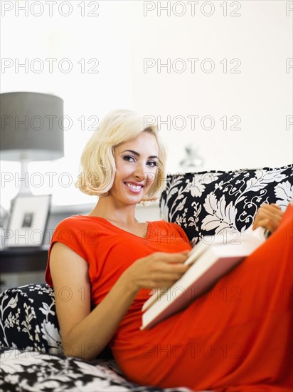 Close-up of woman lying down on sofa and holding book