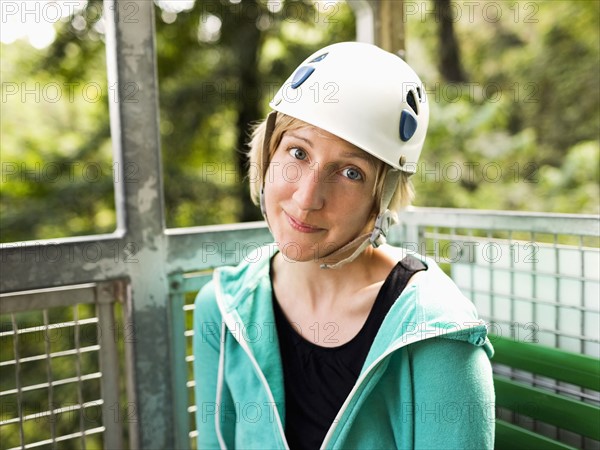 Woman in protective helmet and sitting at net elevator looking at camera