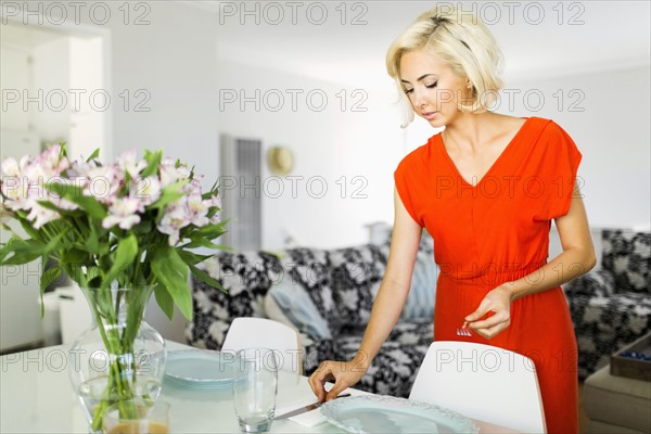 Woman in red dress setting the table