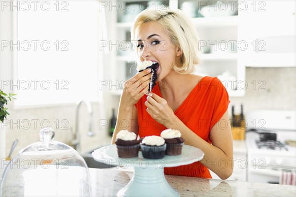 Woman eating muffins at kitchen