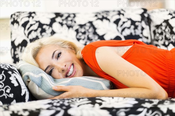 Close-up of woman lying down on sofa and smiling to camera