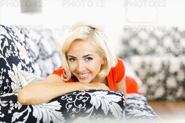 Close-up of woman lying down on sofa and smiling to camera