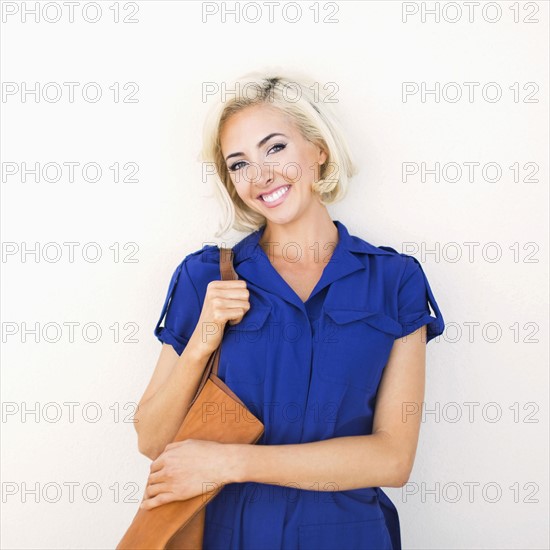 Woman in blue dress and with leather bag posing to camera