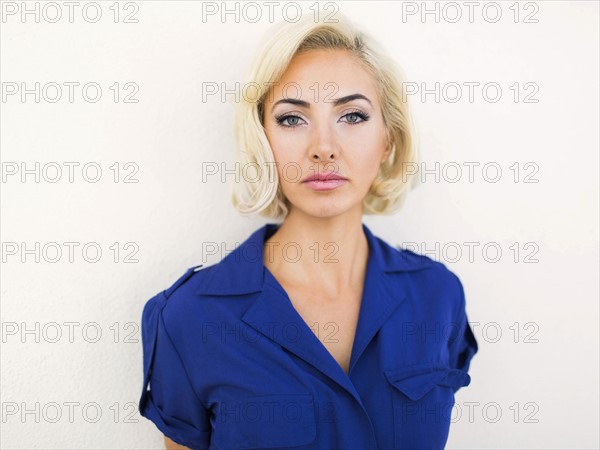 Woman in blue dress posing to camera against white background