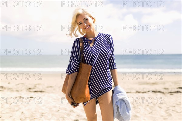 Woman wearing striped blouse posing on sandy beach