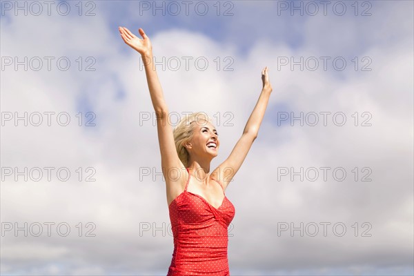 Woman wearing red one piece swimsuit rising arms and smiling