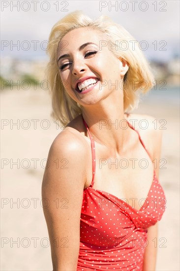 Woman wearing red one piece swimsuit posing on sandy beach