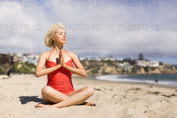 Portrait of blond woman on beach practicing yoga
