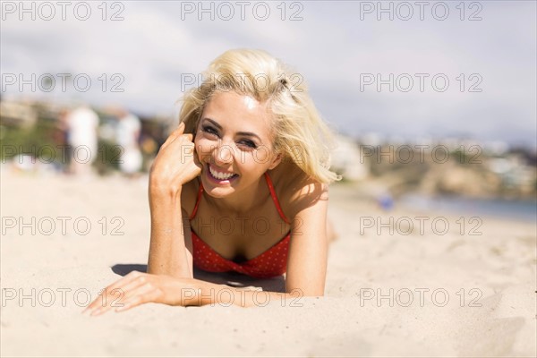 Portrait of blond woman lying on beach