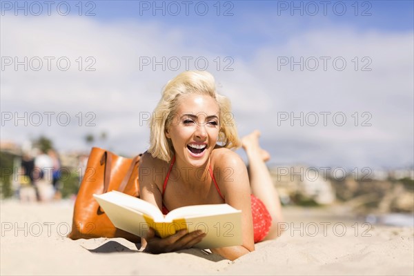 Portrait of blond woman reading book on beach