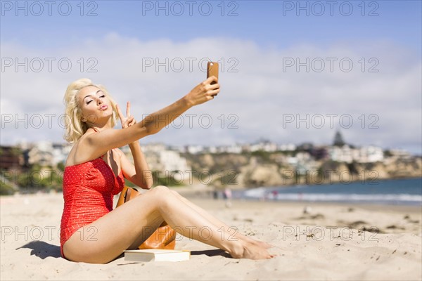 Blond woman taking selfie on beach