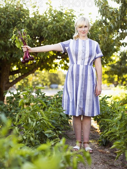 Woman wearing striped dress working in vegetable garden