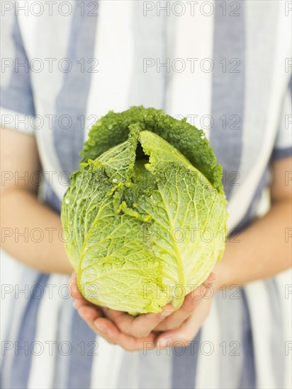 Studio shot of woman holding fresh cabbage