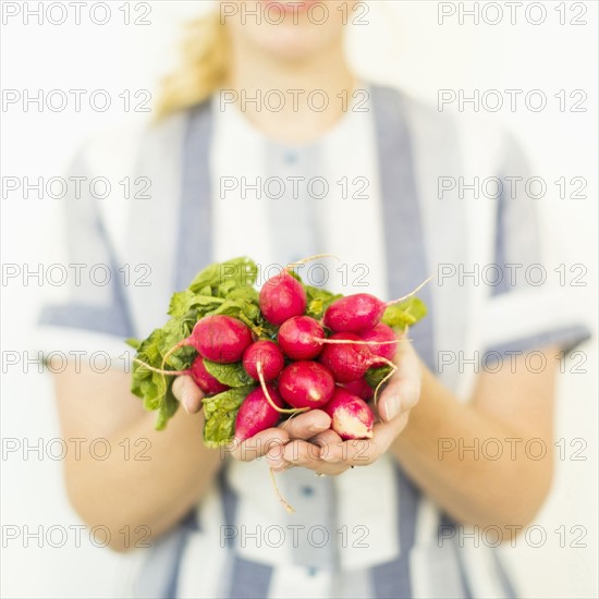 Studio shot of woman holding bunch of fresh radishes