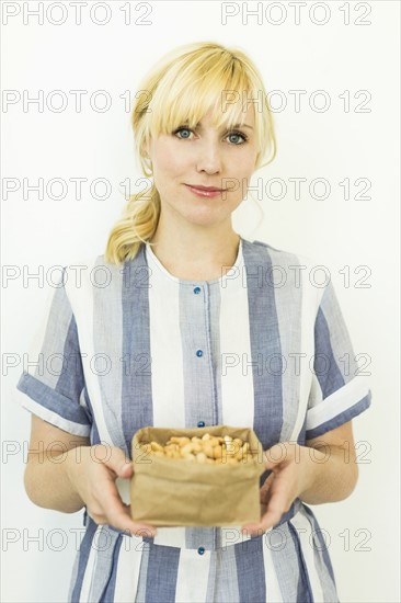 Studio shot of woman holding cashews in paper bag