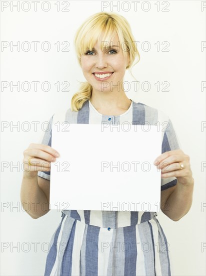 Studio shot of woman holding blank paper