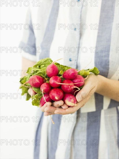 Studio shot of woman holding bunch of fresh radishes