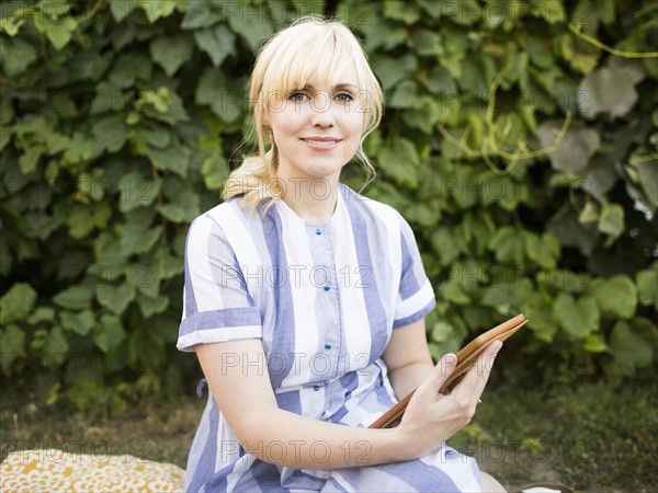 Woman with digital tablet sitting in garden