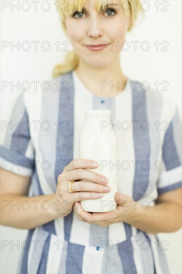Studio shot of woman holding milk bottle