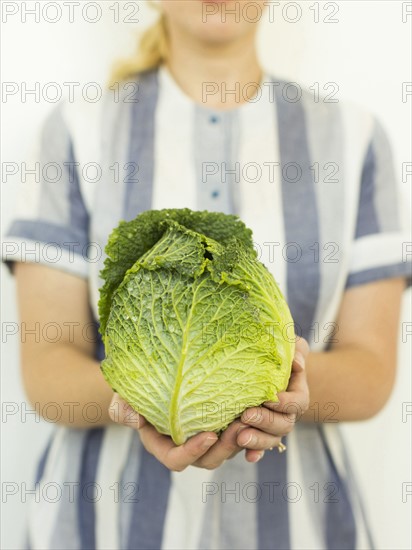 Studio shot of woman holding fresh cabbage