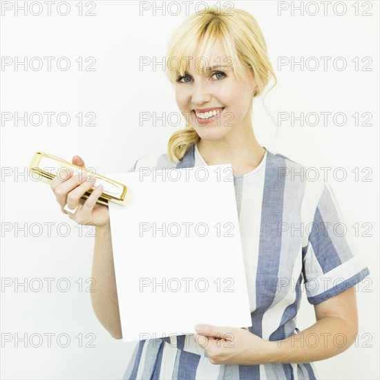 Studio shot of woman holding blank paper and stapler