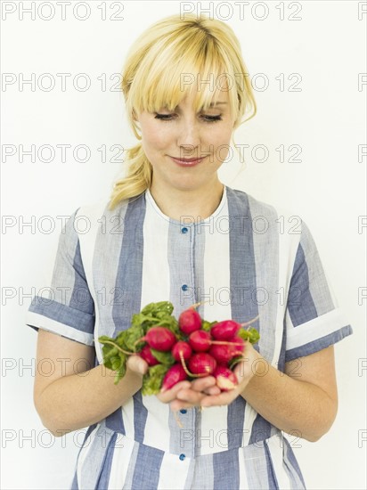 Studio shot of woman holding bunch of fresh radishes