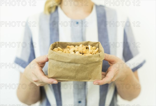 Studio shot of woman holding cashews in paper bag