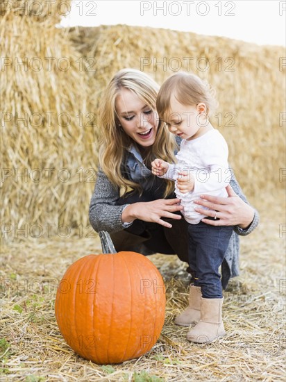 Mother and daughter (12-17 months) looking at large pumpkin