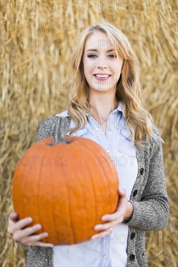 Portrait of young woman holding pumpkin