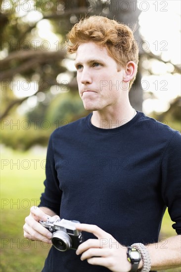 Portrait of young man holding camera