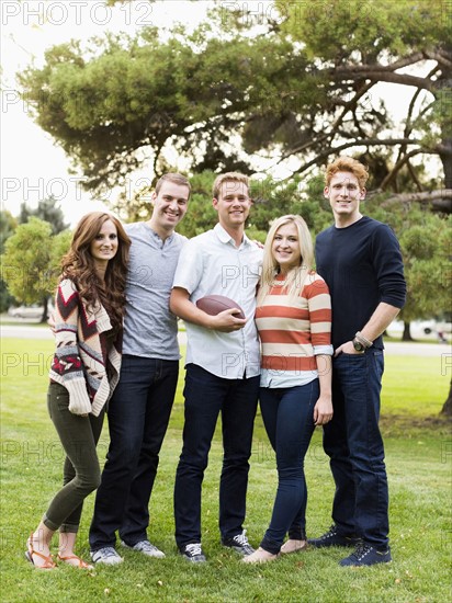 Portrait of friends with football in park