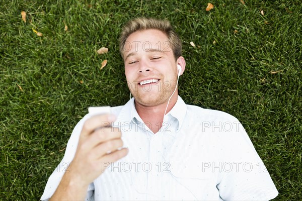 Portrait of young man listening to music in park