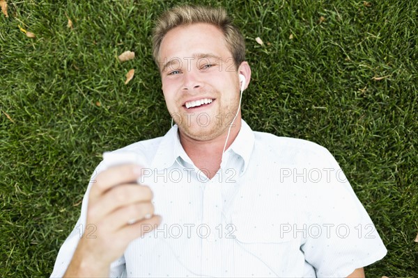 Portrait of young man listening to music in park