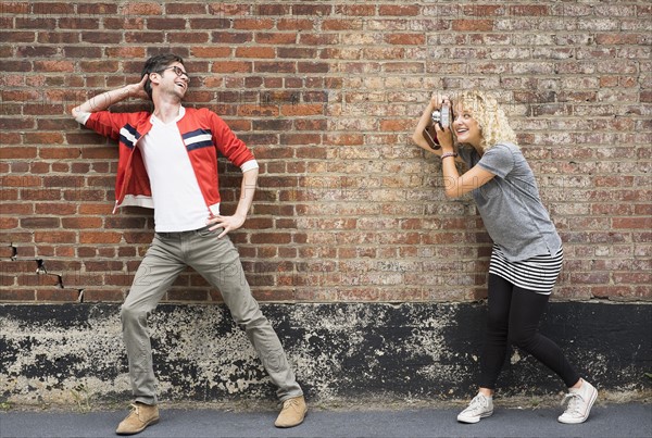 Woman taking pictures of man.