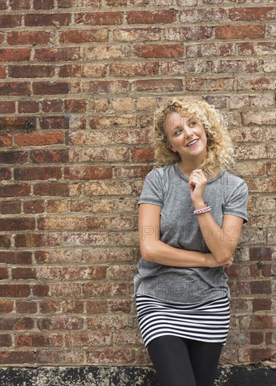 Portrait of young woman in front of brick wall.