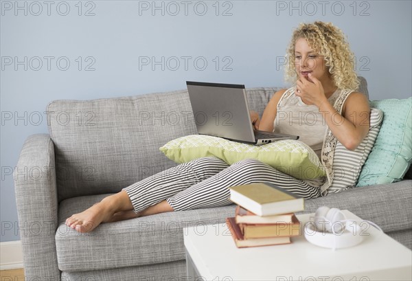 Woman sitting on sofa using laptop.