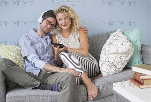 Couple sitting on sofa listening to music.