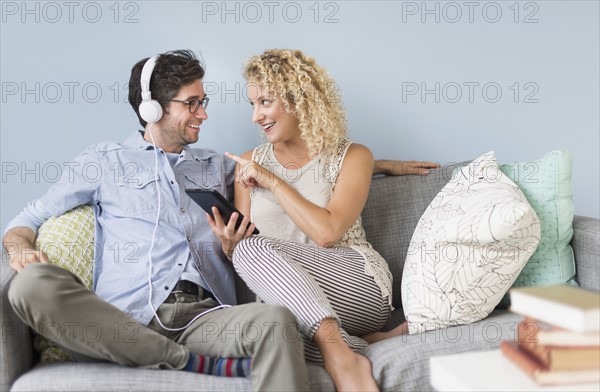 Couple sitting on sofa listening to music.