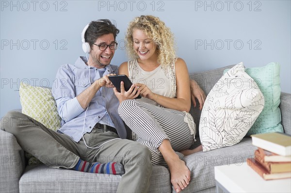 Couple sitting on sofa listening to music.