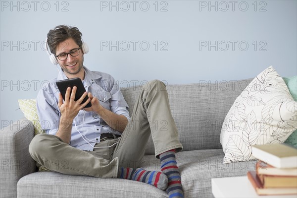 Man sitting on sofa listening to music.