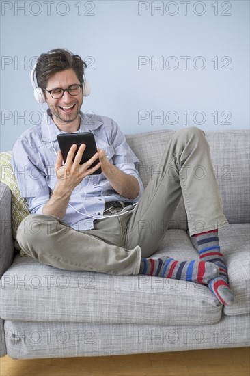 Man sitting on sofa listening to music.