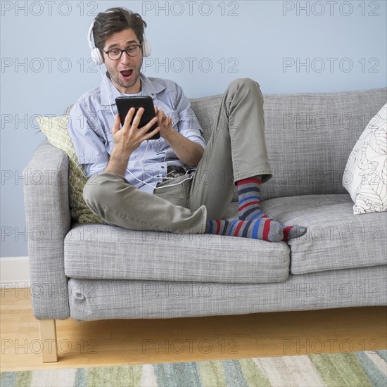 Man sitting on sofa listening to music.