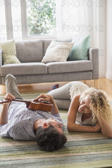 Couple lying on floor playing ukulele.