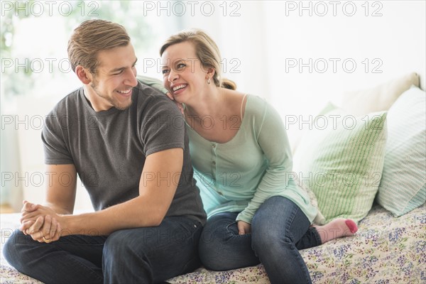 Smiling couple sitting on bed.