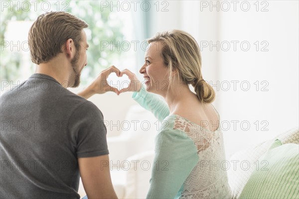 Rear view of couple making heart shape with hands.